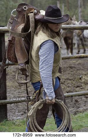 Stock Photo - fence, woman, rope, hat, western, carrying, vest. Fotosearch