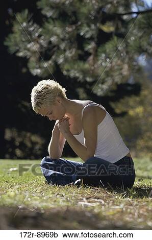 Stock Image - grass, people, woman, sitting, outdoors, contemplation, blond. Fotosearch