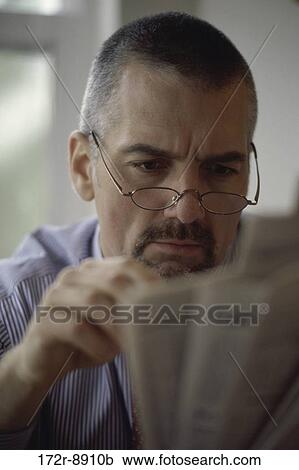 Stock Image - people, newspaper, eyeglasses, reading, Middle-aged, serious. Fotosearch