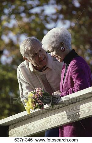 Stock Photograph - people, smiling, railing, talking, couple, conversation, senior. Fotosearch