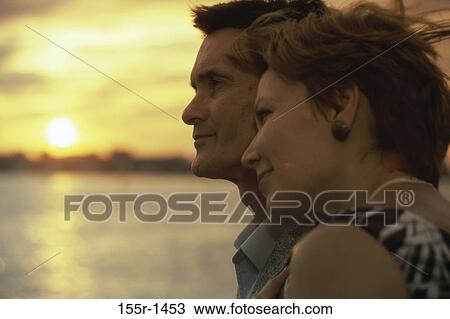 Stock Image - people, water, staring, couple, sunset, beach, leaning. Fotosearch