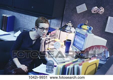 Stock Image - desk, woman, eyeglasses, computer, business, casual, cluttered. Fotosearch