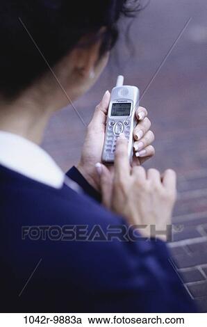 Stock Image - dial, dialing, woman, Hispanic, phone, business, outdoors. Fotosearch