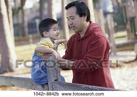 Stock Image - fence, people, Asian, sitting, outdoors, park, family. Fotosearch