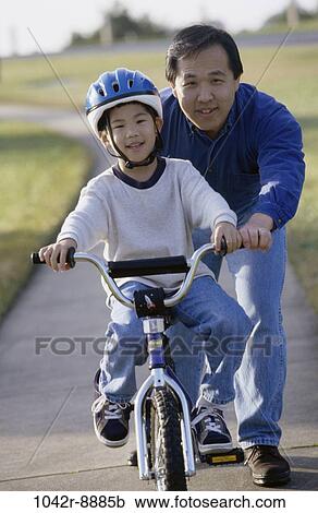 Stock Image - grass, people, Asian, bicycle, helmet, outdoors, bike. Fotosearch