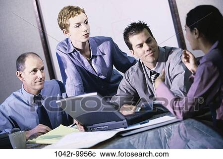 Stock Image - meeting, multiethnic, men, women, desk, table, papers. Fotosearch