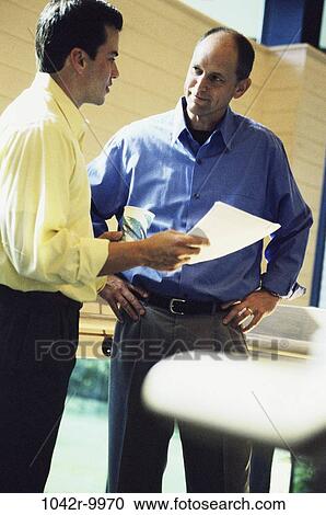 Stock Image - multiethnic, men, conversation, papers, business, Middle-aged, businessmen. Fotosearch