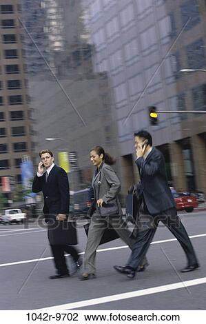 Stock Image - multiethnic, people, walking, talking, phone, city, street. Fotosearch