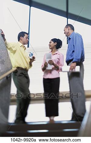 Stock Image - multiethnic, stairs, business, Middle-aged, indoors, casual dress, businesspeople. Fotosearch