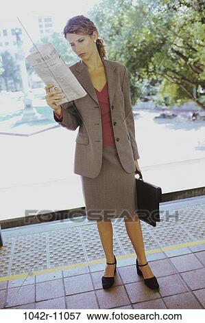 Stock Photo - paper, woman, newspaper, briefcase, information, reading, standing. Fotosearch