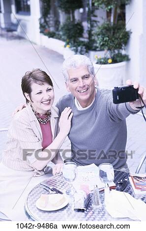Stock Image - people, couple, outdoors, Middle-aged, dining out, camera, vacation. Fotosearch