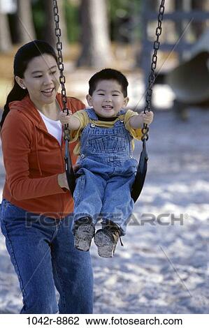 Stock Image - people, playing, Asian, mother, swinging, swing, playground. Fotosearch
