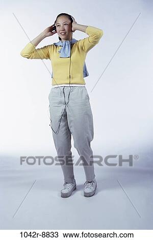 Stock Image - people, woman, headset, Asian, listening, music, indoors. Fotosearch