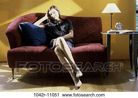 Stock Image - people, woman, stylish, lamp, pillow, sitting, couch. Fotosearch