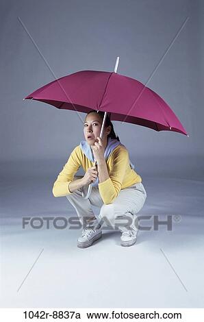 Stock Image - people, woman, umbrella, Asian, open, weather, frightened. Fotosearch
