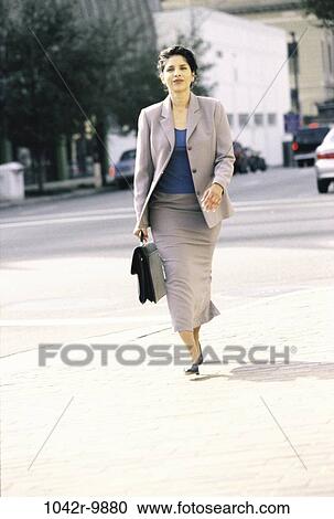Stock Image - woman, walking, briefcase, Hispanic, confident, business, outdoors. Fotosearch