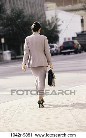 Stock Image - woman, walking, briefcase, Hispanic, back, business, outdoors. Fotosearch