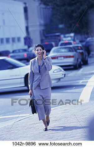 Stock Photograph - woman, walking, briefcase, talking, phone, business, outdoors. Fotosearch