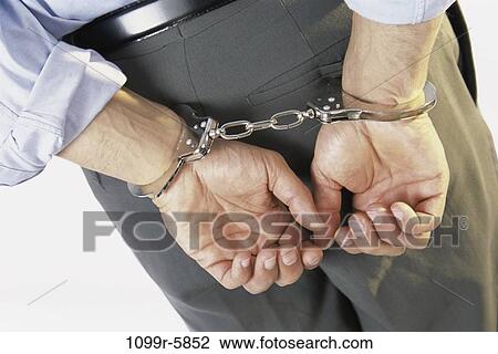 Stock Image - business, businessman, indoors, arrest, criminal, handcuffs. Fotosearch