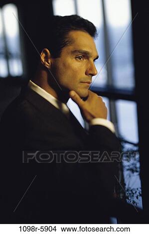 Picture - Hispanic, business, Middle-aged, contemplating, businessman, indoors. Fotosearch