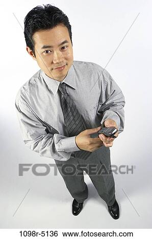Stock Photograph - indoors, phone, businessman, cell phone, business, Asian. Fotosearch