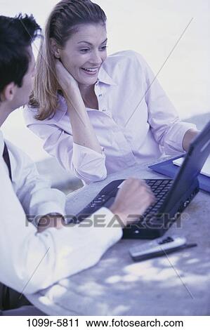 Stock Image - laptop, phone, business, outdoors, cell phone, Caucasian, casual dress. Fotosearch