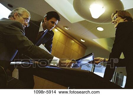 Picture - meeting, group, men, desk, woman, paperwork, folder. Fotosearch
