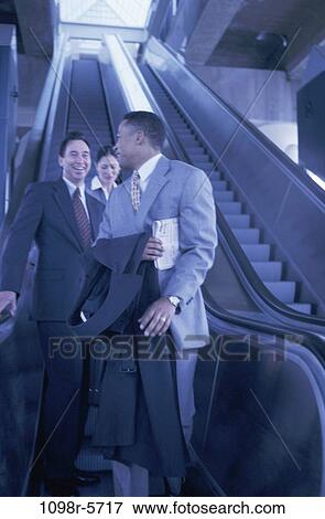 Stock Photo - multiethnic, escalator, business, Middle-aged, indoors, travel. Fotosearch
