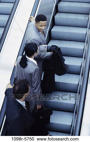 Stock Image - multiethnic, people, escalator, business, Middle-aged, indoors. Fotosearch