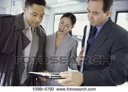 Stock Image - multiethnic, talking, papers, business, looking, forms, travel. Fotosearch
