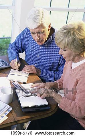 Stock Image - people, couple, senior, writing, finance, bills, personal finance. Fotosearch