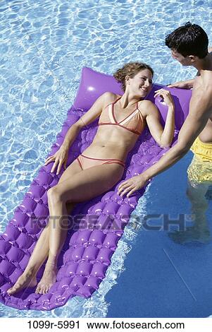 Stock Image - people, swim, floating, pool, couple, swimming, raft. Fotosearch