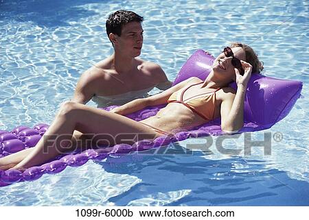 Stock Image - people, swim, floating, pool, couple, swimming, sunglasses. Fotosearch