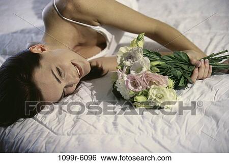 Stock Photograph - people, woman, bed, holding, flowers, bouquet. Fotosearch