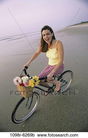 Stock Image - people, woman, bicycle, beach, riding, flowers, basket. Fotosearch