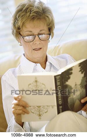 Stock Photo - people, woman, eyeglasses, senior, reading, book, indoors. Fotosearch