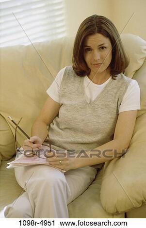 Stock Image - people, woman, eyeglasses, sofa, brunette, indoors, Caucasian. Fotosearch