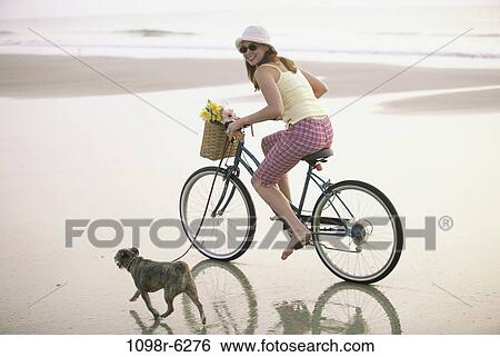 Stock Photograph - people, woman, walking, dog, bicycle, pet. Fotosearch