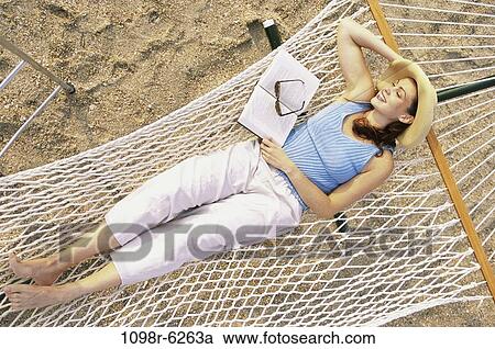 Stock Image - sand, people, woman, hat, sleeping, reading. Fotosearch
