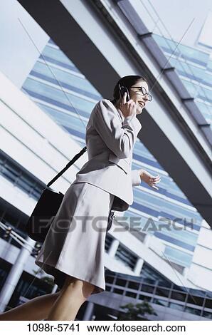 Stock Image - woman, buildings, talking, Hispanic, phone, modern, business. Fotosearch