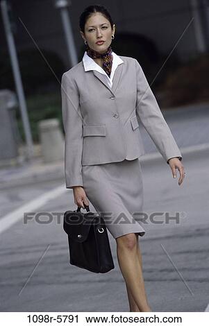 Stock Image - woman, walking, briefcase, Asian, Hispanic, business, outdoors. Fotosearch