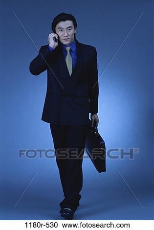 Stock Image - briefcase, talking, Asian, business, cell phone, businessman. Fotosearch