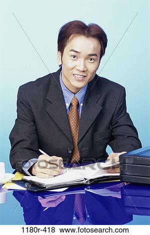 Stock Photo - desk, Asian, business, businessman, indoors, young adult. Fotosearch