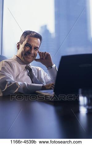 Stock Image - desk, Hispanic, laptop, business, Middle-aged, businessman. Fotosearch