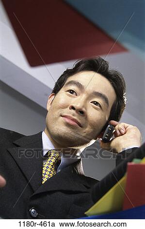 Stock Image - desk, talking, Asian, phone, business, Middle-aged. Fotosearch