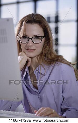 Stock Image - desk, woman, eyeglasses, computer, business, indoors, Caucasian. Fotosearch