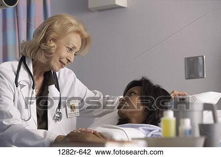 Stock Image - multiethnic, women, bed, calm, patient, doctor, stethoscope. Fotosearch