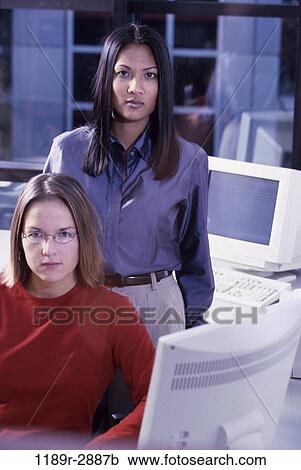 Stock Image - multiethnic, women, desk, business, computers, serious, casual. Fotosearch
