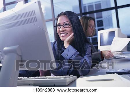 Stock Image - multiethnic, women, desk, eyeglasses, computer, business, using. Fotosearch