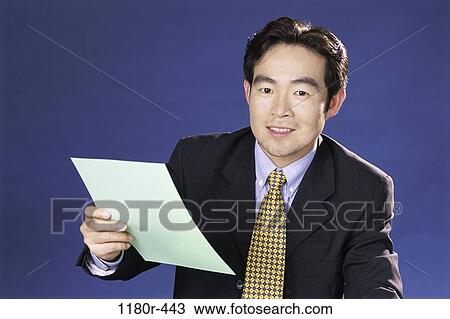 Stock Image - paperwork, Asian, business, businessman, indoors, young adult. Fotosearch